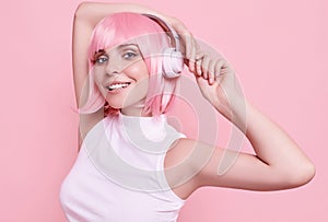 Bright sexy hipster girl with pink hair enjoys the music in headphones