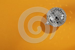 Bright shiny disco ball on orange background, top view. Space for text