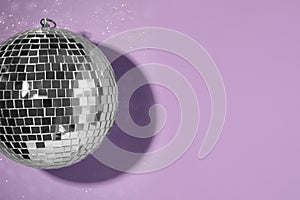 Bright shiny disco ball on violet background, top view. Space for text