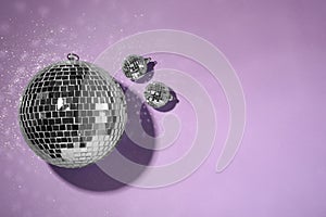 Bright shiny disco balls on violet background, flat lay. Space for text