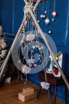 Bright shiny stars, Christmas tinsel on blue background hang on bamboo sticks of the wigwam