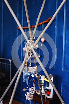 Bright shiny stars, Christmas tinsel on blue background hang on bamboo sticks of the wigwam