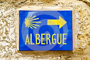 Of bright signboard with word ALBERGUE on a stone wall with direction to the right photo