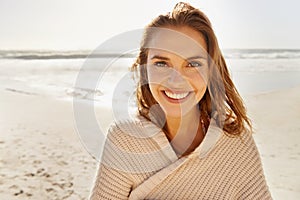 Bright smile in the bright sunshine. Portrait of a beautiful young woman standing on the beach in casual wear.