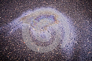 A bright spot of oil or gasoline spray on the pavement after rain. Oil stain on the asphalt, rainbow-shaped colored