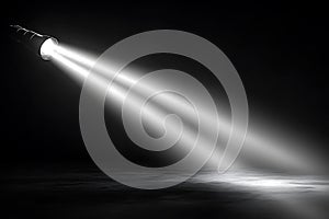 Bright spotlight illuminates a dark empty stage with dramatic beams of light shining