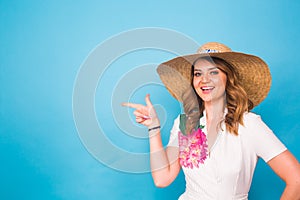 Bright studio portrait of attractive young woman pointing copyspace on blue background.