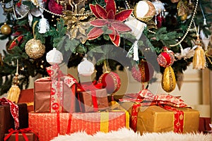 Bright studio shot of gift boxes in front of a gorgeous lush Christmas tree, decorated in red and gold.