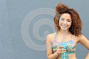 Bright summer trendy portrait of young fit Latina girl walking on the street, wearing vivid crop top, long curly afro hair