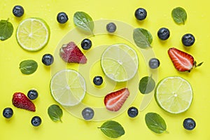 Bright summer yellow background with slices of citrus lime mint blueberry strawberry berries Flat lay