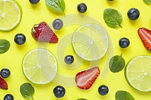 Bright summer yellow background with slices of citrus lime mint blueberry strawberry berries Flat lay