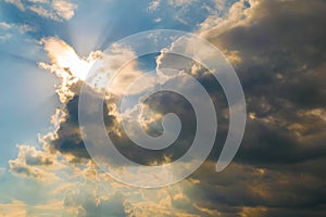 Bright sun illuminating the clouds from behind with light rays