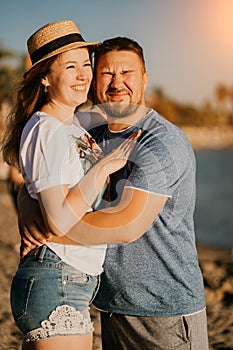 bright sun. a man and a woman in love squinting from the sun hug on the beach.