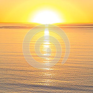 Bright sun reflected in the calm water at sunset photo