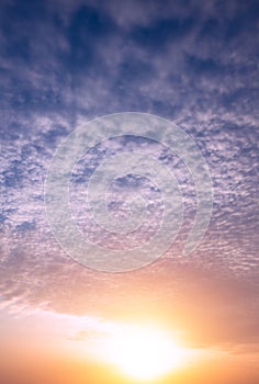 Bright sun at sunset on the background of clouds and blue sky