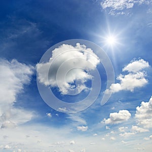 Bright sun and white clouds on the background of an blue sky.