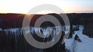 Bright sunny landscape with snowy ground and pine tree forest. Clip. Aerial view of the sunrise in winter, dense forest