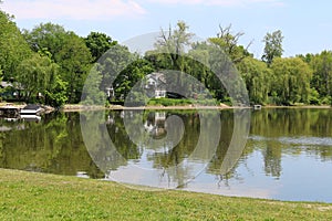 Bright sunny tree lined lake reflection blue sky