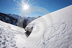 Bright sunny winter landscape tirol, snow covered alp hut and love heart