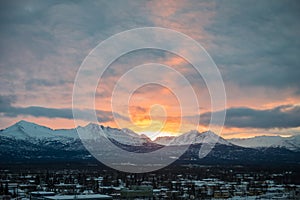 Bright sunrise behind mountains on a cloudy winter day