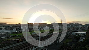 Bright sunrise over elevated railroad tracks next to small town and mountains