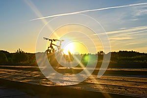 Bright sunrise on the road near the river on the background of a bicycle. Mountain bike in forest with sun rays.