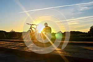 Bright sunrise on the road near the river on the background of a bicycle. Mountain bike in forest with sun rays