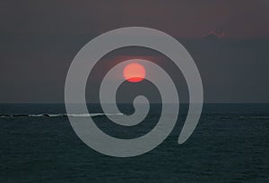 Bright sunset with large red sun under the ocean surface