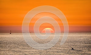 Bright sunset with large yellow sun under the sea surface.