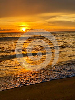 Bright sunset over the ocean with a golden sky and reflections on water