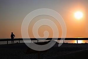 Sunset over the sea and road, traffic devider and dark silhouette of man with cap on his head,, Horizontal. Mideterranian, cyprus photo