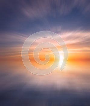 Bright sunset with rays on the background of soft clouds over the sea
