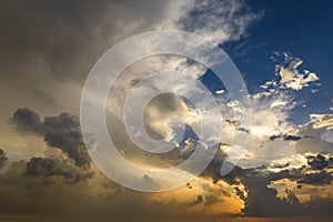 Bright sunset with setting sun behind vivid orange and yellow clouds