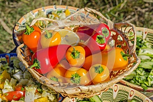 Bright sweet bell pepper in a beautiful wicker basket against the background of grass