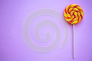 Bright swirl lollipop on purple background with copy space