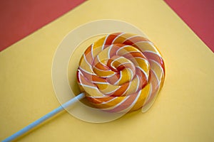Bright swirl lollipop on yellow and orange background