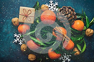 Bright Tangerines Green Leaves Pine Cones Gift Box Snow Flakes on Dark Blue Background.Sparkling Glitter Lights Christmas New Year