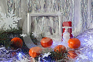 Bright tangerines, Santa Claus figurine , photo frame on the background of festive tinsel, side view - the concept of wonderful