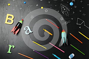 Bright toy rockets, school supplies and drawings on chalkboard