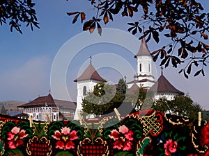 Bright, traditional rugs with painted monastery in background, Romania