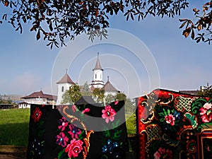 Bright, traditional rugs with painted monastery in background, Romania