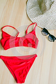 Bright trendy bikinis on a wooden background, as well as a straw hat with wide brim