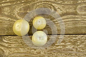 Bright unripe yellow tonatoes close up flat lay photo on brown textured wooden background