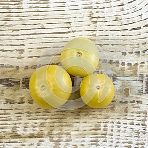 Bright unripe yellow tonatoes close up flat lay photo on white textured wooden background