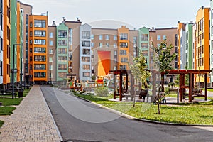 Bright urban landscape of a new residential area with modern multi-apartment colored houses and a well-maintained house