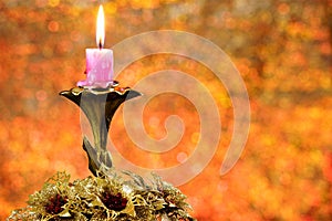 Bright vintage candle with Christmas gold flowers, on a background of rainbow bokeh lights. Applicable for holiday decoration,