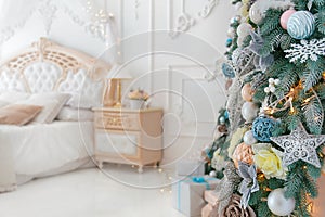 Bright White Bedroom Interior with Christmas New Year Tree decor and lights bokeh