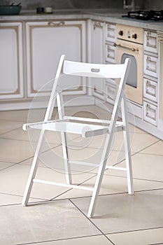 Bright white comfortable simple wooden folding chair out of focus interior kitchen background.