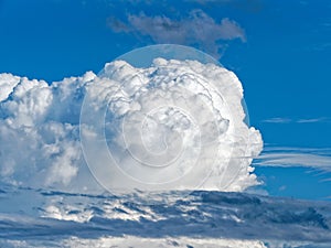 Huge white Cumulus cloud towering in the blue sky