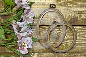 Bright white and pink flowers Alstroemeria and small frames on browm wooden textured background close-up